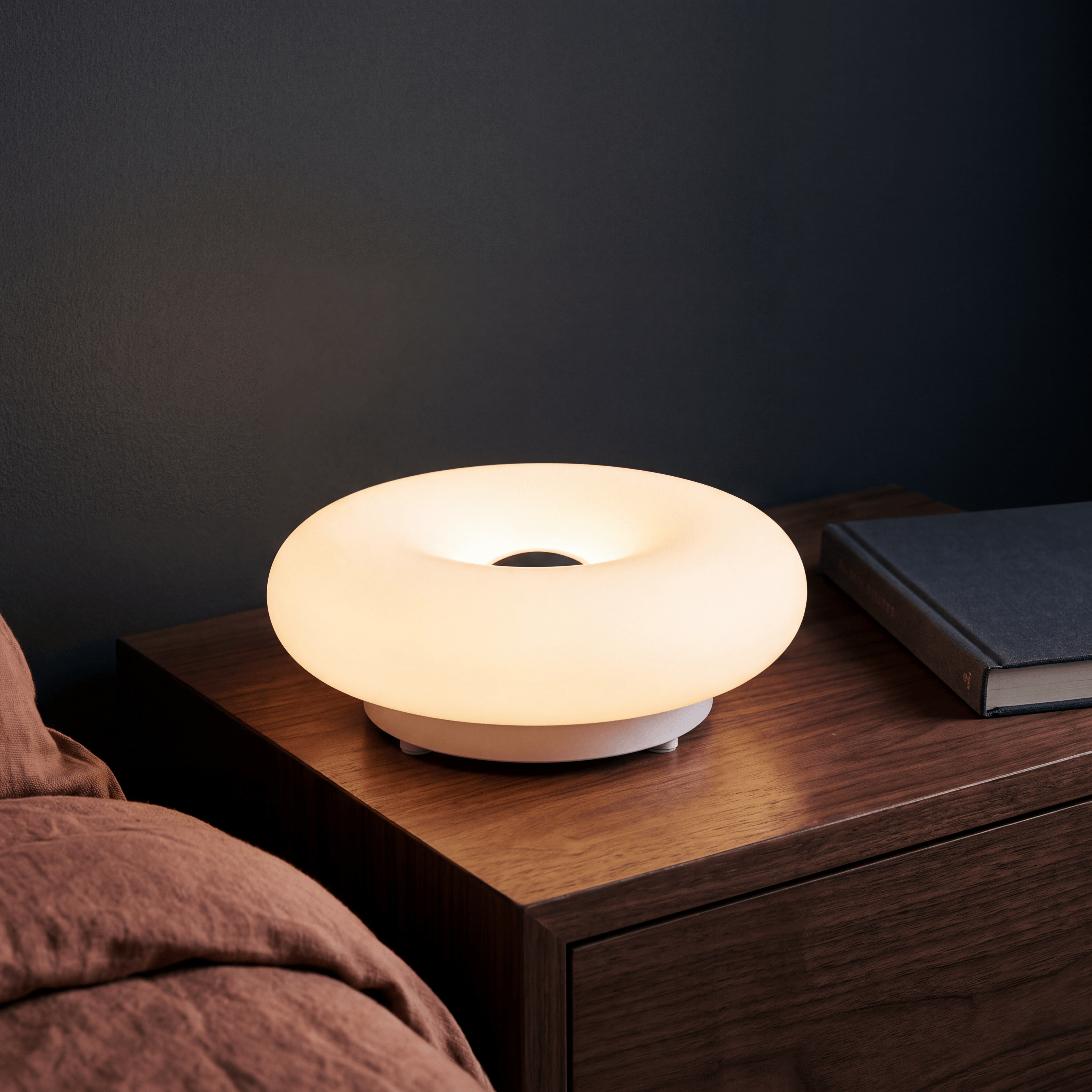 Bauhaus donut lamp glowing warm on a bedside table