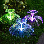 SeaBloom solar jellyfish garden light with fibre-optic head glowing blue and green in a garden at night
