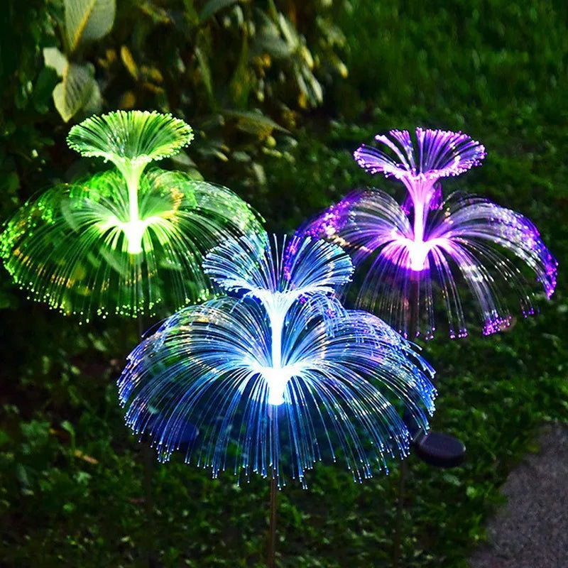 SeaBloom solar jellyfish garden light with fibre-optic head glowing blue and green in a garden at night