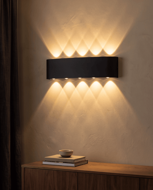 Aura Beam black LED wall light casting warm up-and-down beams on a wall above a wooden console table