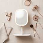 Overhead flat lay of the GlowVanity makeup mirror surrounded by brushes, a compact and a folded cloth
