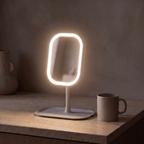 GlowVanity lighted vanity mirror glowing on a wooden surface against a dark plaster wall