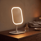 GlowVanity LED makeup mirror glowing warm white on a wooden dresser beside perfume bottles
