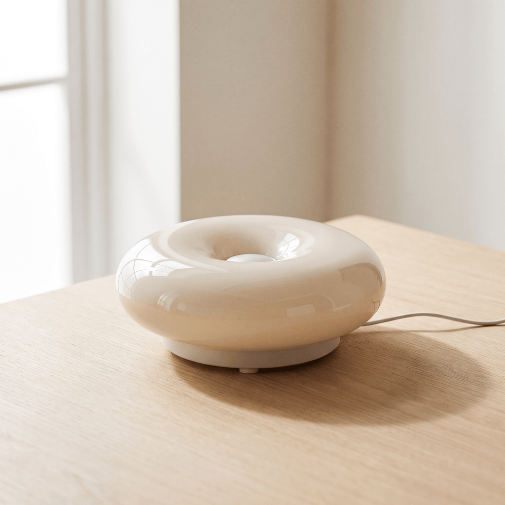 Halo Bauhaus donut lamp switched off on a pale wood table in daylight, showing its rounded white shade