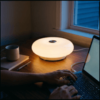 Halo donut lamp lighting a desk at night beside a laptop and mug as someone types