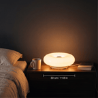 Halo donut lamp on a bedside table with a mug and book, shown at 30 cm wide