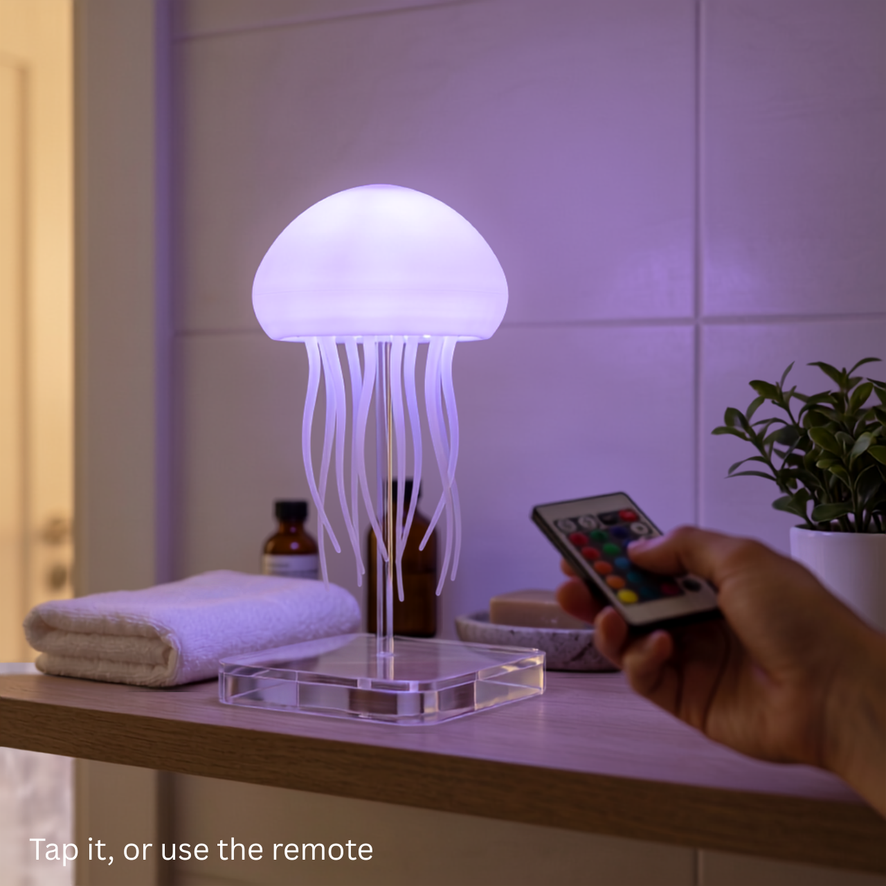Jelly jellyfish lamp glowing purple as a hand points the included remote at it