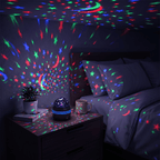Starlull projector scattering red, green and blue star dots across a dark bedroom from a bedside table