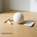 Luna moon lamp switched off on a wooden table with the flat-pack wooden stand pieces included in the box