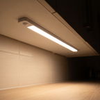 Nook Light motion sensor bar casting warm light under a kitchen cabinet onto the counter