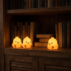 Peep duck night lights glowing on a wooden bookshelf among old hardback books
