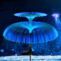 SeaBloom solar jellyfish garden lights glowing green and blue beside a garden path at night