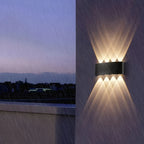 Aura Beam wall light glowing on a balcony wall during heavy rain at dusk