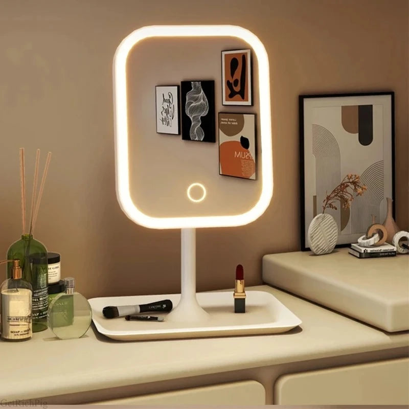 GlowVanity lighted mirror on a cream vanity with photos tucked into the frame, lipstick and a reed diffuser